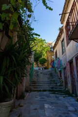 Fototapeta na wymiar Street in Athens with graffiti and lots of greenery, with stairs up