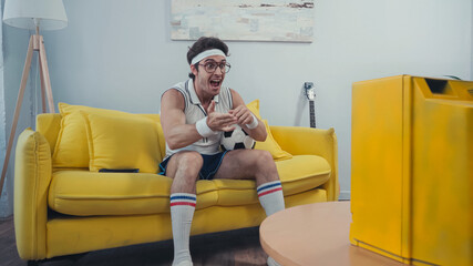 excited football fan with soccer ball gesturing while watching game on retro tv