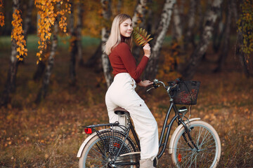 Plakat Happy active young woman ride bicycle in autumn park. Fall season,