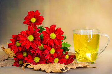Scena con una tazza di te e un mazzo di crisantemi posato su delle foglie gialle in autunno in italia