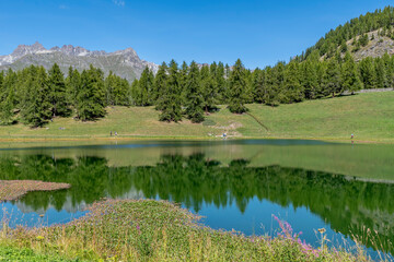 The surrounding nature is reflected in the still water of Lake Lod, Aosta Valley, Italy, in the...