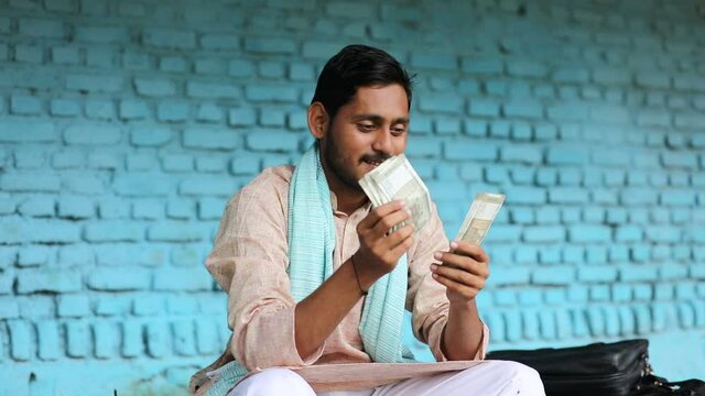 Happy Indian farmer counting money at home.