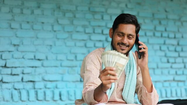 Happy Indian farmer showing money at home.