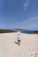 Chico atletico tatuado posando en dunas de arena