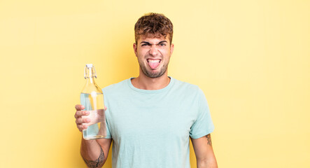 young handsome man feeling disgusted and irritated and tongue out. water concept