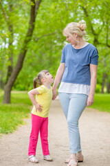 Fototapeta premium Little girl with syndrome down walks with her mother in a summer park