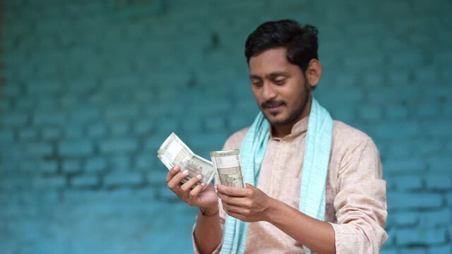 Happy Indian farmer counting money at home.