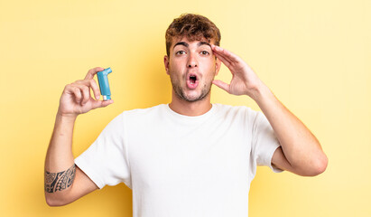 young handsome man looking happy, astonished and surprised. asthma concept