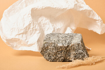 dry grass, crumpled white paper and natural stone on a beige background, background for the presentation