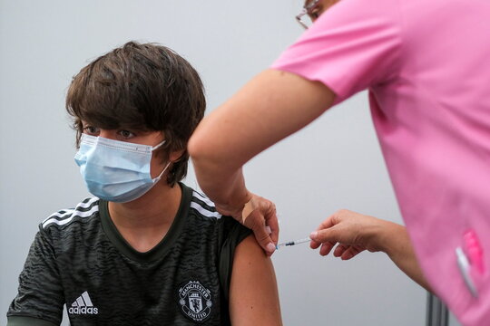 A boy receives COVID-19 vaccine at a vaccination centre in Seixal