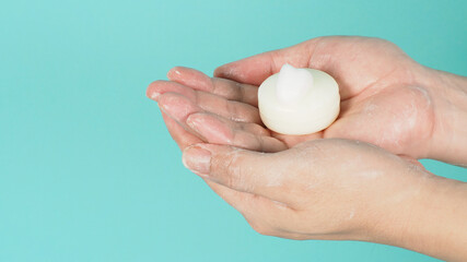 Hands washing gesture with Bar soap and bubble on mint green or Tiffany Blue background.
