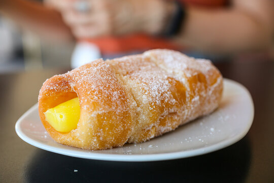 Graffa fritta ricoperta di zucchero e ripiena di crema pasticciera 