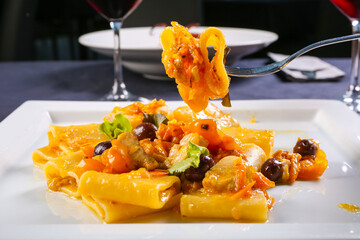 Piatto da ristorante con pasta di Gragnano con pomodoro giallo, olive nere e zucca