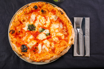 Pizza Margherita napoletana con pomodoro, mozzarella di bufala e basilico fresco fotografata dall'alto su uno sfondo nero