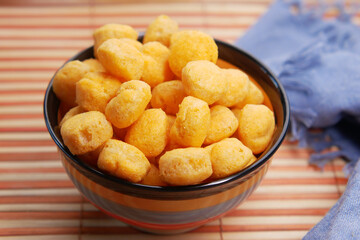puffed corn rings chips in black bowl on white background