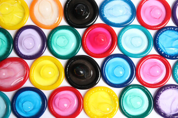 Unpacked colorful condoms on white background, top view. Safe sex