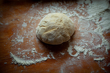 raw wheat dough on a wooden kitchen board in flour