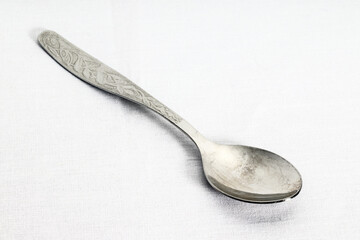 shiny teaspoon on white fabric background, close-up
