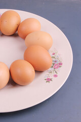 Randomly stacked pile of raw chicken eggs on a white plate