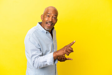 Cuban Senior isolated on yellow background surprised and pointing side