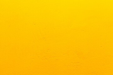 Old yellow wall in spots, cracks, stains. Painted concrete wall in abstract grunge style loft. Vintage wall background texture for backgrounds, portraits, posters.