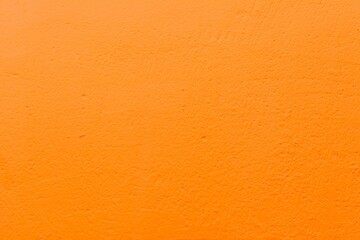 Naklejka premium Old orange wall in spots, cracks, stains. Painted concrete wall in abstract grunge style loft. Vintage wall background texture for backgrounds, portraits, posters.