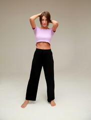 Fototapeta na wymiar Beautiful slender model in black trousers and purple top.