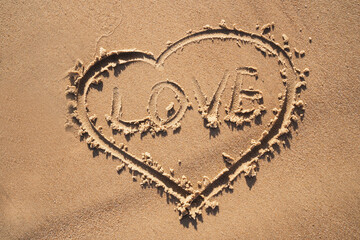 Drawing of a heart on the sand. Inscription LOVE on the sand. Romantic inscription for Valentine's Day.