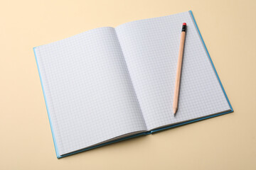 Open notebook with blank sheets and pencil on beige background