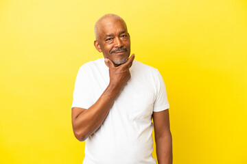 Cuban Senior isolated on yellow background having doubts and thinking