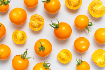 Ripe fresh yellow orange tomatoes with green tails on light gray background flat lay top view. Cherry tomatoes. Vegetables, healthy vegan organic food, harvest concept tomatoes pattern layout cooking