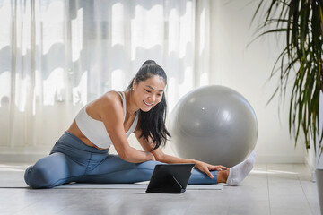 Young Asian woman exercising at home, attending an online yoga class