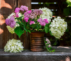 Still life with a bouquet of white and lilac flowers in a ceramic vase. Blooming hydrangea. Vintage.