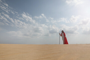 Fototapeta premium Jesus Christ walking with stick in desert. Space for text