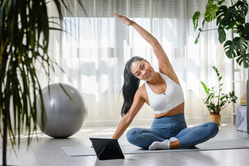 Young Asian woman exercising at home, attending an online yoga class