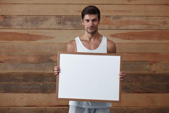 Young smiling european man hold empty white frame