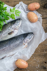 Two raw trout with potatoes on wooden table
