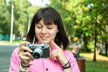 A young girl with a camera walks in a city park.