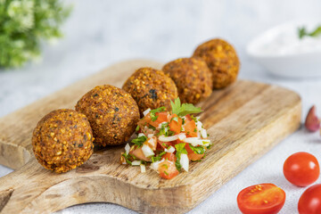 Falafel, a traditional Middle Eastern dish made from chickpeas, served with tomato salad. Vegetarian food. Great healthy snack. Close-up