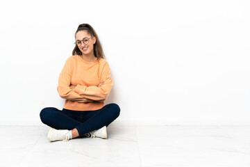 Young woman sitting on the floor with arms crossed and looking forward