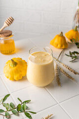  a natural smoothie made from yellow pumpkin. autumn drink with honey and milk. on a light background, vertical position