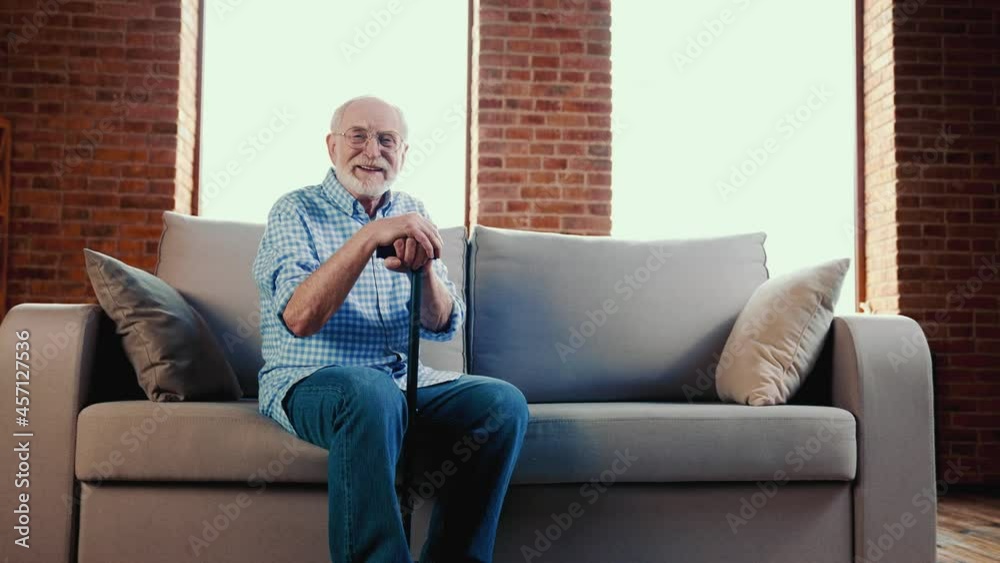 Poster cheerful positive relaxed grandpa enjoy sofa rest hold walk cane