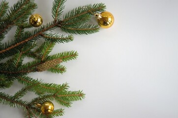 Branches of the Christmas tree with gold balls on a white background with a place for recording New Year's greetings, flat layout