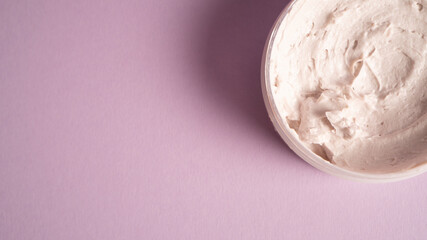 Cosmetic face mask on purple background. Pink facial mask cream. White skin care advertising ideas