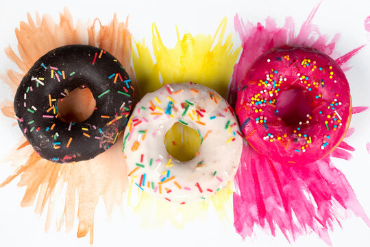 Creative sweet food. A stack of glazed colorful assorted donuts on a bright watercolor painted background.