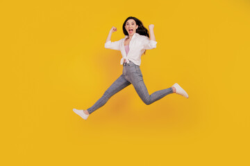 Fototapeta na wymiar Portrait of crazy sporty active girl raise fists open mouth jump run on yellow background
