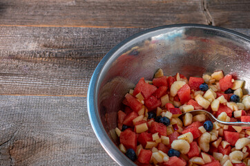 Fresh chopped and marinated fruits in a bowl isolated on wooden table 