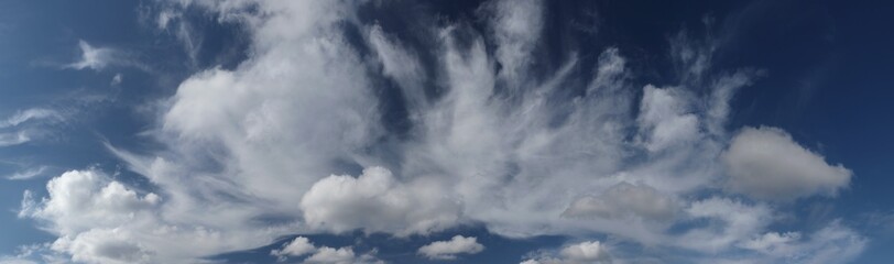 High resolution deep blue summer sky panorama with white cirrus and cumulus clouds. Late summer sky, windy weather.