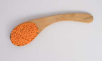 Red Lentils on a wooden spoon isolated on white background