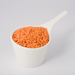 white cup full of red lentils isolated on white